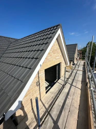 Dark roof tiles and pale brick gable completed on the new extension.