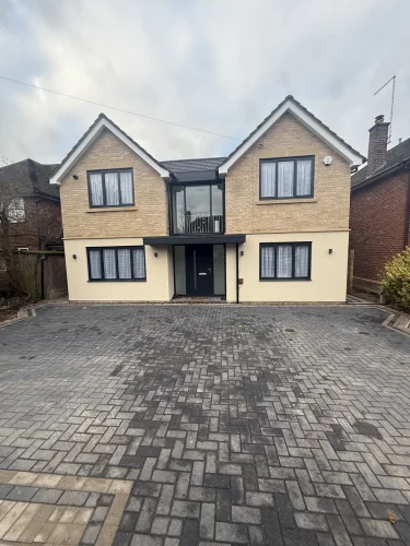 Completed front elevation with twin gables, pale brickwork and new block paving.