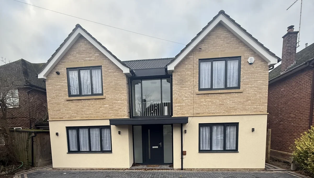 Completed front elevation with twin gables, pale brickwork and new block paving.