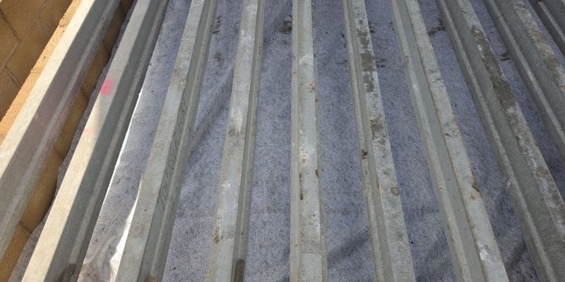Precast concrete floor beams spanning the extension footprint over a geotextile membrane covering the oversite, with the blockwork sleeper wall alongside