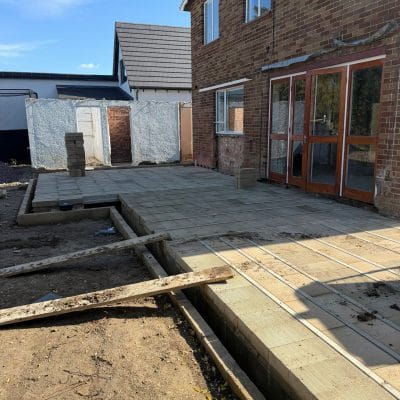 The completed beam-and-block ground floor across the extension footprint, with new timber glazed doors installed in the rear elevation of the existing house