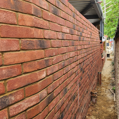 Raking view along a new facing brick elevation showing consistent coursing and aligned perpend joints