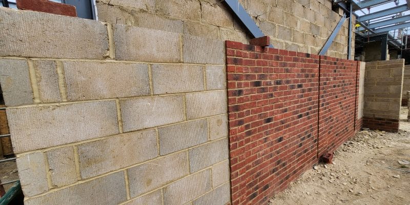 Cavity wall under construction with a blockwork inner leaf on the left and a red facing brick outer leaf on the right