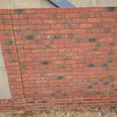 New facing brickwork in stretcher bond with even mortar joints, toothed into blockwork on the left and weep vents in the base course