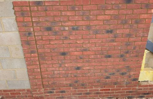 New facing brickwork in stretcher bond with even mortar joints, toothed into blockwork on the left and weep vents in the base course