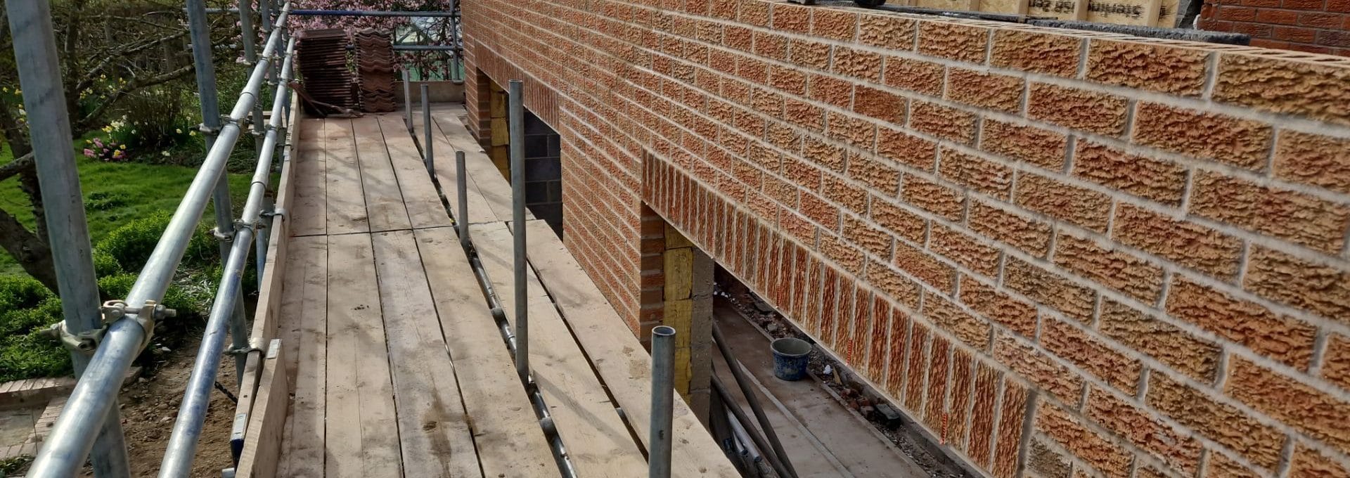 Long run of new facing brickwork on an extension, showing consistent coursing and an opening with its lintel in place