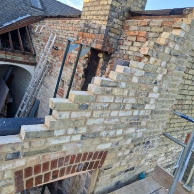 New yellow gault stock brickwork racked back in steps where it meets the existing red brick wall and chimney stack on a Cambridge extension
