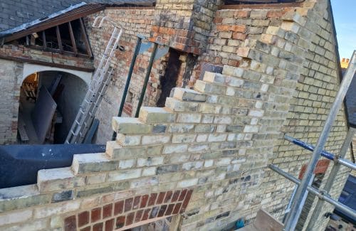New yellow gault stock brickwork racked back in steps where it meets the existing red brick wall and chimney stack on a Cambridge extension