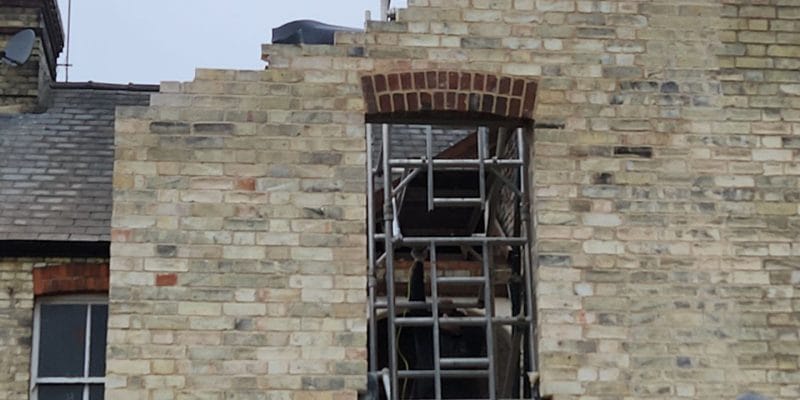 New red brick segmental arch with radiating voussoirs over a first-floor window opening in a new yellow gault brick gable